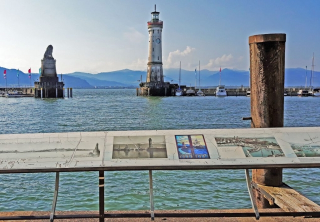 Blick auf historische Schautafel vor der Lindauer Hafenausfahrt mit Löwenskulptur und Leuchtturm (06/2021)